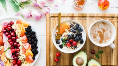 Plain yogurt, kefir, milk, cheese, berries and nuts beside an unsweetened fortified plant beverage on a bright table.