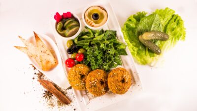 Apple with nut butter, yogurt and berries, vegetables with hummus, roasted chickpeas, nuts, seeds and fruit arranged as simple anti-inflammatory snacks.