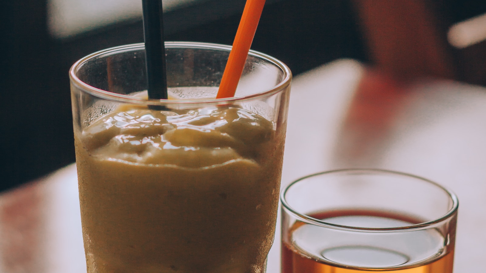 Water with citrus, unsweetened tea, coffee, a berry spinach smoothie and a simple milk beverage arranged on a bright table.