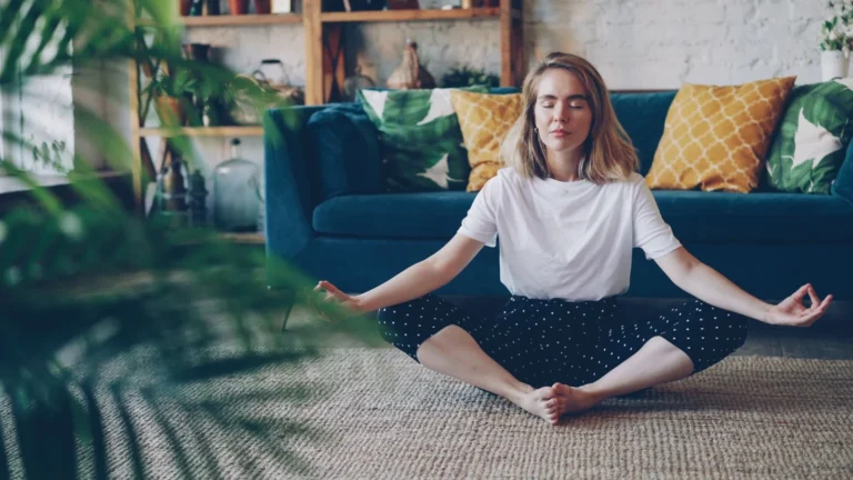 Adult seated calmly in a living room practicing slow mindful breathing.
