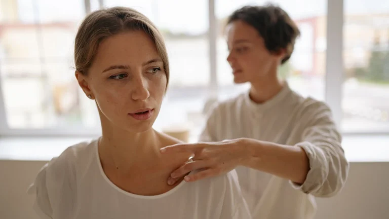 Professional therapist giving a gentle shoulder massage without targeted pressure on the side of the neck.
