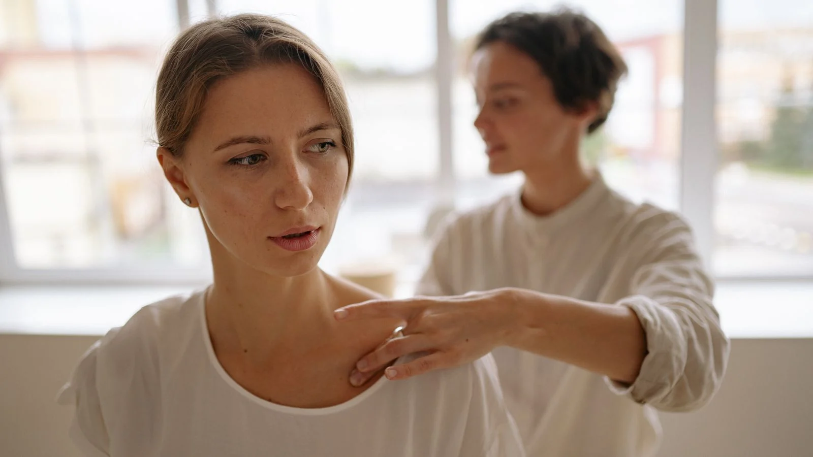 Professional therapist giving a gentle shoulder massage without targeted pressure on the side of the neck.
